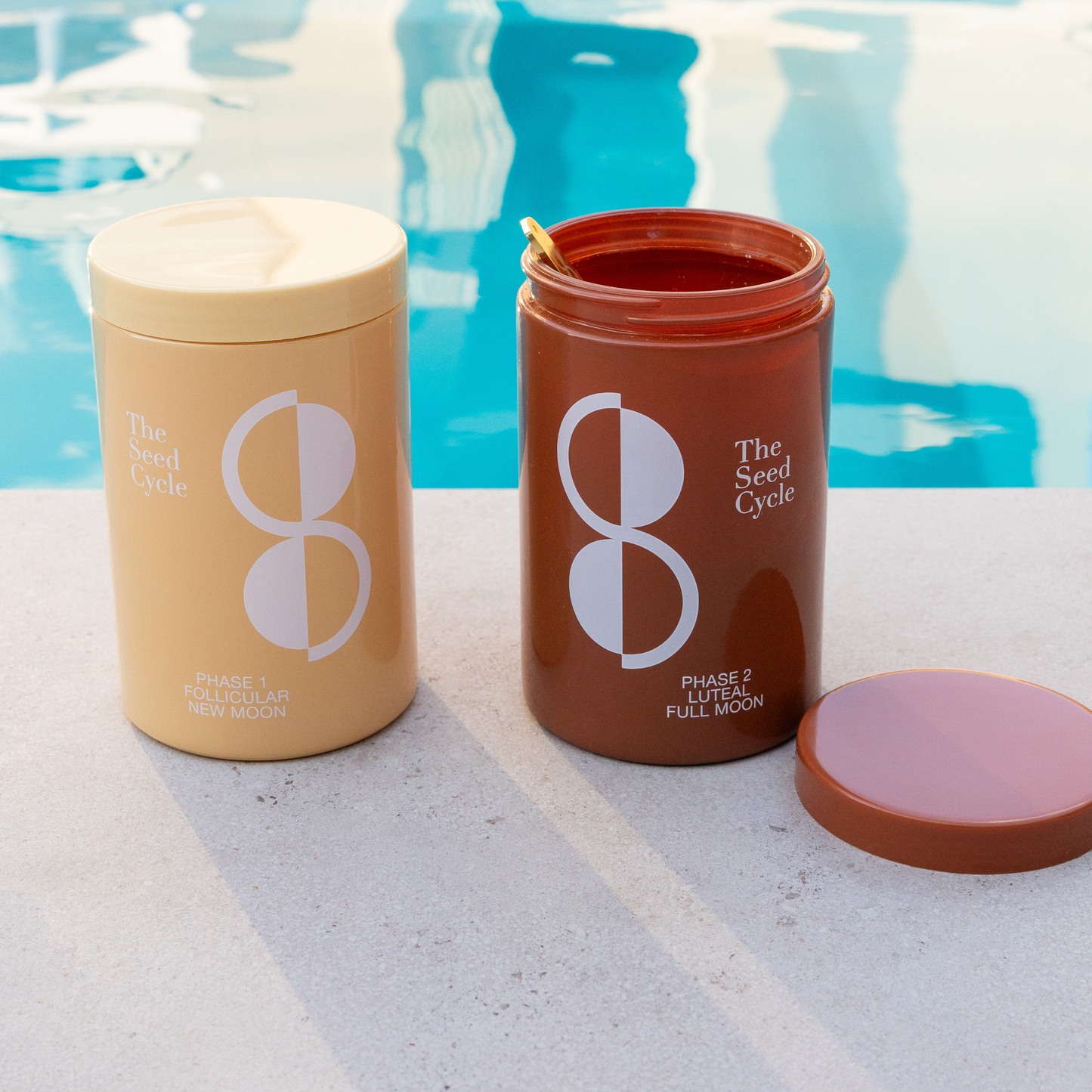 The Seed Cycle Phase 1 and Phase 2 seed cycling jars sitting poolside on a sunny day